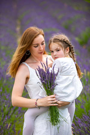 Mother walks with her little daugher holding a bouquet of lavander in Czech republicの写真素材