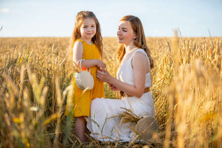 Beautiful young mother and her daughter at the wheat field in sunny day in Czech republicの写真素材