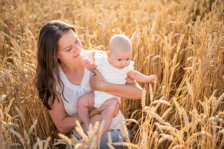 Beautiful young mother and her daughter baby girl at the wheat field in sunny day in Czech republicの写真素材