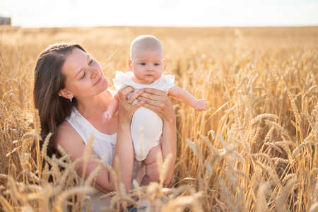 Beautiful young mother and her daughter baby girl at the wheat field in sunny day in Czech republicの写真素材