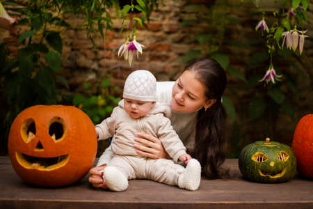 Young Mother and daughter sitting near pumpkins, Halloween eveの写真素材