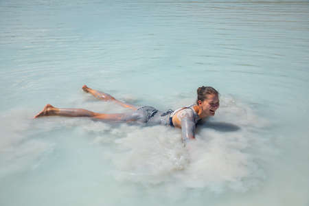 Happy and funny female tourist takes smears natural cosmetic clay to his body on Salda lake, Turkeyの写真素材