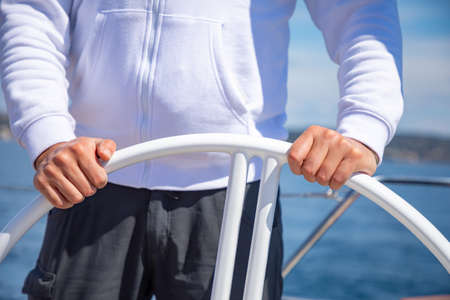 Yachtsman holding the wheel on a sailing boat during yachting, Croatiaの写真素材