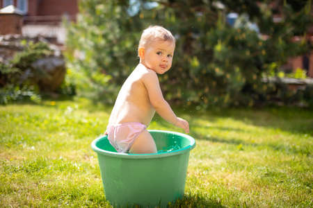 Baby girl flop in a basin with water on home backyard in summer timeの写真素材