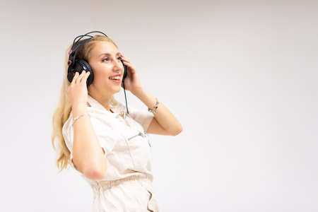 Beautiful young blonde woman listening music on white background