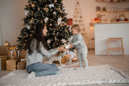 Happy family mother and child daughter near Christmas tree at home