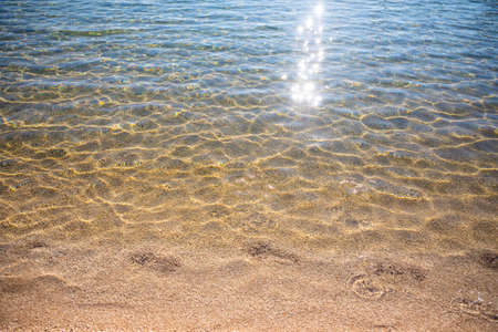 Ripples on surface of sand sea bottom, clear and calm blue sea water, fishes in water, nature textureの写真素材