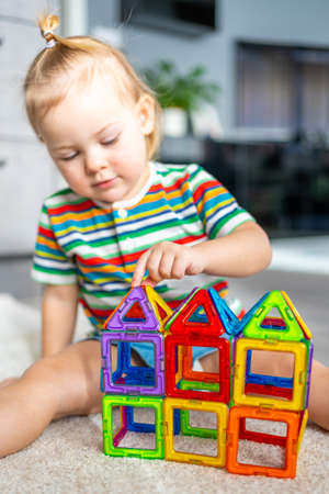 Little girl playing colorful magnet plastic blocks kit at home. The child playing educational games. Early childhood development.の写真素材