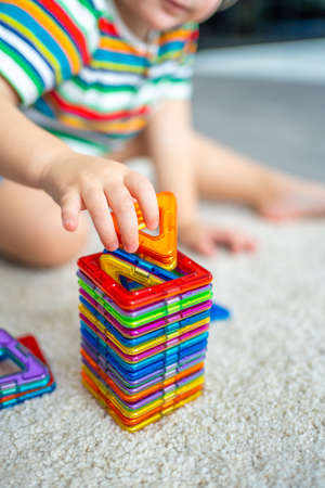 Little girl playing colorful magnet plastic blocks kit at home. The child playing educational games. Early childhood development.の写真素材