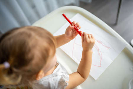 Cute little girl painting with felt-tip pen at home. Creative games for kids. Stay at home entertainmentの写真素材