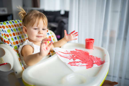 Cute little girl painting with fingers at home. Creative games for kids. Stay at home entertainmentの写真素材