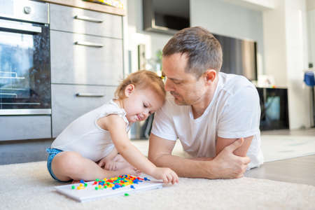 Cute little girl playing with mushroom nail mosaic. Father and baby playing together concept. Hobby and leisure time.の写真素材