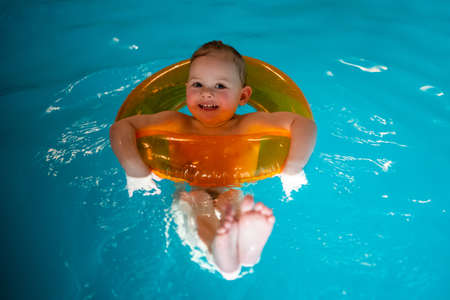 Baby girl in the private home swimming pool in a swimming circle enjoys splashing