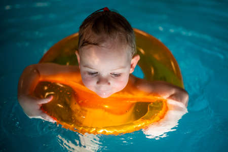 Baby girl in the private home swimming pool in a swimming circle enjoys splashingの写真素材