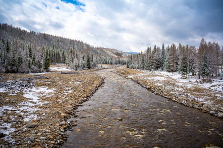The not frozen bed of a beautiful winding Chibit River flowing through a snow-covered valley...