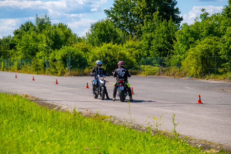 Prague, Czech Republic - July 12, 2022: Male instructor controls L-driver while she doing exercise of driving bike in skill training motordrome. Europian driver schoolのeditorial素材