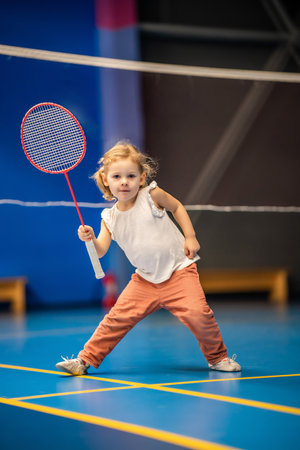 Little girl three years old playing badminton in sport wear on indoor court . High quality photoの写真素材