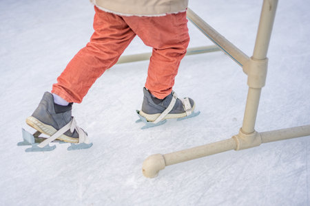 Feet of little daughter learning to skate in winter in one of Prague ace rink. High quality photo