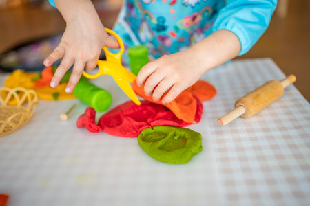 A little girl playing with plasticine. Sensory development and experiences, themed activities with children, fine motor skills development. High quality photoの写真素材