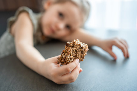 Close-up view of piece of cookies with banana and seeds in little girl hand. High quality photoの写真素材