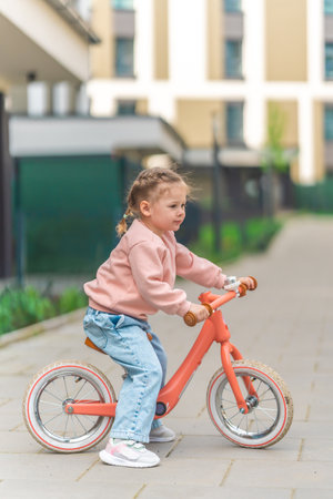 Little girl riding balance bike in the courtyard of the residence in Prague, Europe. High quality photoの写真素材