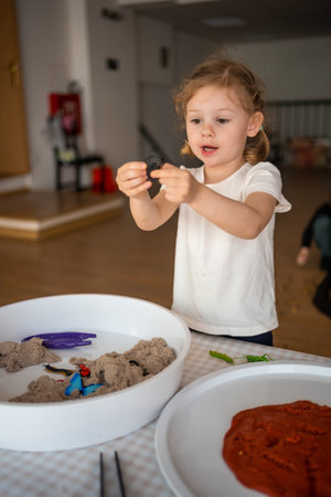 Little girl playing with kinetic sand and toys insect. Sensory development and experiences, themed activities with children, fine motor skills development. High quality photoの写真素材