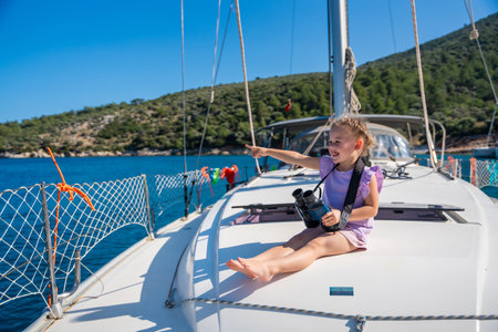Little girl on a yacht looking through binoculars in the sea. High quality photoの写真素材