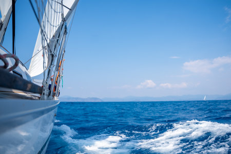 Yacht sailing in an open sea. Close-up view of side of the boat. Clear sky after the rain, waves and water splashes. High quality photoの写真素材