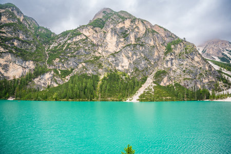 Braies lake surrounded by pine forests and the rocky ranges of the Dolomites in cloudy day, Italy. High quality photoの写真素材