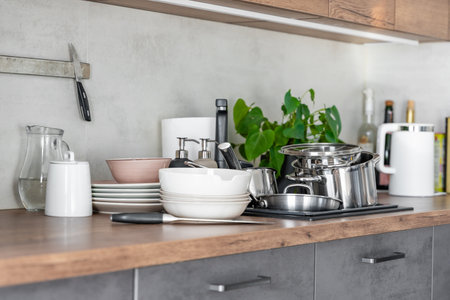 Dirty dishes and unwashed kitchen appliances filled the kitchen sink. High quality photo