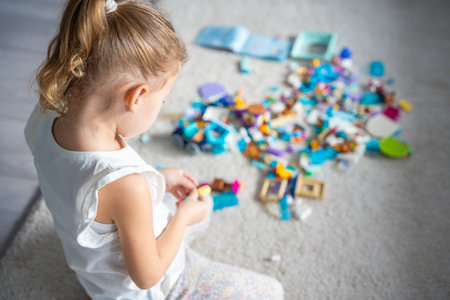 Little girl play with constructor toy on floor in home, educational game, spending leisure activities time concept. Focus on child. High quality photoの写真素材