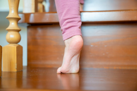 Closeup of little girl foot going up the stairs at home, child climbing stairs. High quality photo