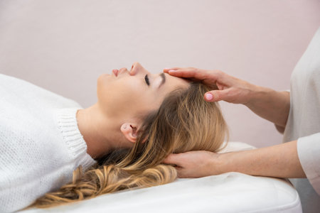 Healer performing set of 32 points of access bars on young woman head, stimulating positive change thoughts and emotions in salon. Alternative medicine. High quality photoの写真素材