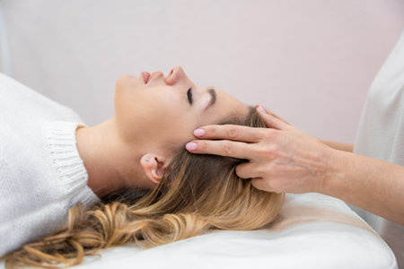 Healer performing by lightly touched set of 32 points of access bars on young woman head, stimulating positive change thoughts and emotions. Alternative medicine. High quality photoの写真素材