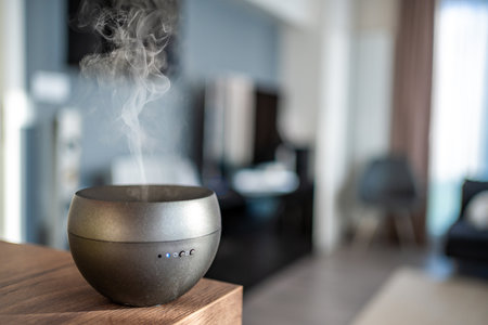Gray aroma oil diffuser on light table at home, space for text. Air freshener. High quality photo