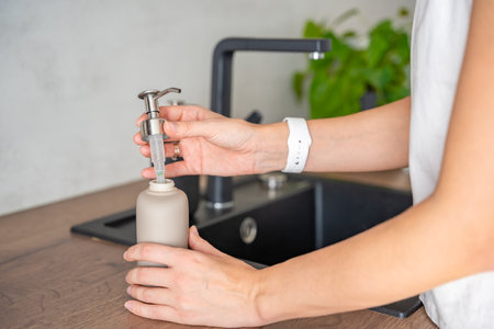 A woman uses soap or detergent in a reusable bottle. Eco-friendly lifestyle. High quality photoの写真素材