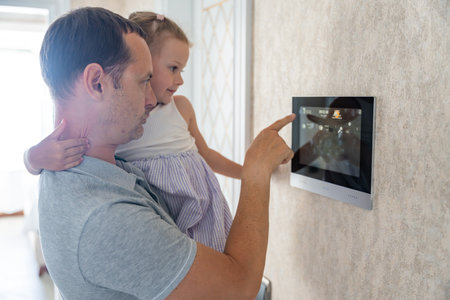 Daughter in her father using tablet panel application for control smart home living. Wireless device...