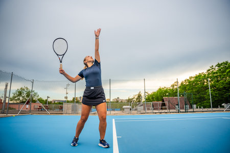 Professional female tennis player serving the tennis ball during playing on outside court. High quality photoの写真素材