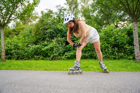 Roller skater woman warming up in park before rollerblading on inline skates. Outdoor activities. Summer roller skating. High quality photoの写真素材