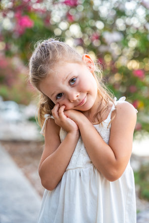 Portrait of little girl in white dress happy smiling on blooming park background in Croatia. High quality photoの写真素材