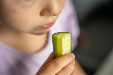 Close up view of little girl eats fresh cucumber. Summer organic food. High quality photoの写真素材