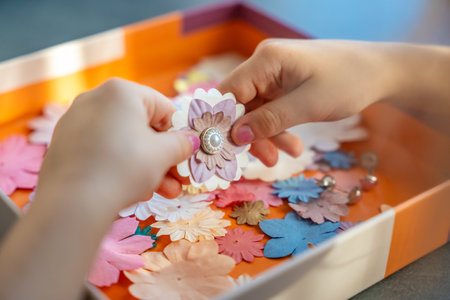 Small, colorful paper flowers in child hands, little girl creativing of 3D flowers. Child development toy. High quality photoの写真素材
