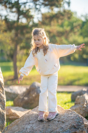 Little girl having fun and jumping on stones in the autumn park in Prague, Europe. High quality photoの写真素材