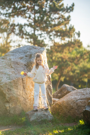Little girl having fun and jumping on stones in the autumn park in Prague, Europe. High quality photoの写真素材
