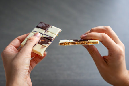 Piece of trend white chocolate with halva paste in woman hands. Confectionery handmade sweets at home in the kitchen. High quality photoの写真素材