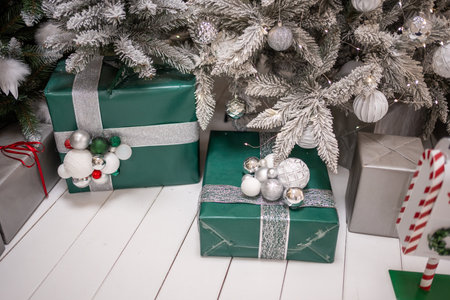 Gifts under Christmas tree with white and silver toys. Festively decorated Christmas tree with garlands. Symbol of the new year in traditional colors. High quality photoの写真素材