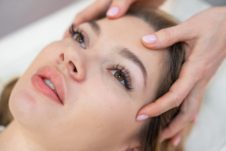 Healer performing set of 32 points of access bars on young woman head, stimulating positive change thoughts and emotions. Alternative medicine concept. High quality photoの写真素材