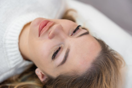 Close up face of beautiful woman lying on spa bed before procedure in cosmetology clinic. High...