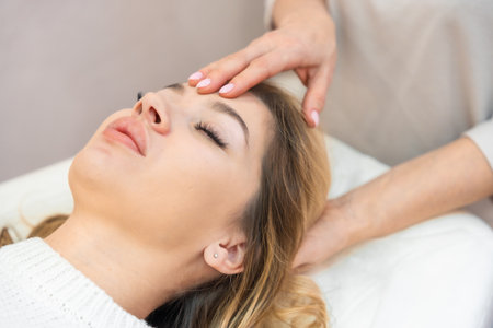 Healer performing by lightly touched set of 32 points of access bars on woman head, stimulating positive change thoughts and emotions. Alternative medicine concept. High quality photoの写真素材