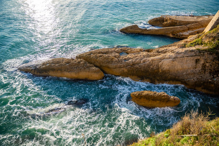 View of a sunlit rocky coastline with the sea shimmering under a clear blue sky in Ulcinj, Montenegro. High quality photoの写真素材